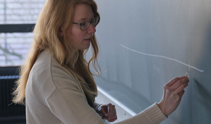 Banner Mirte Kuipers, blond haar en bril,  tekenend op een schoolbord