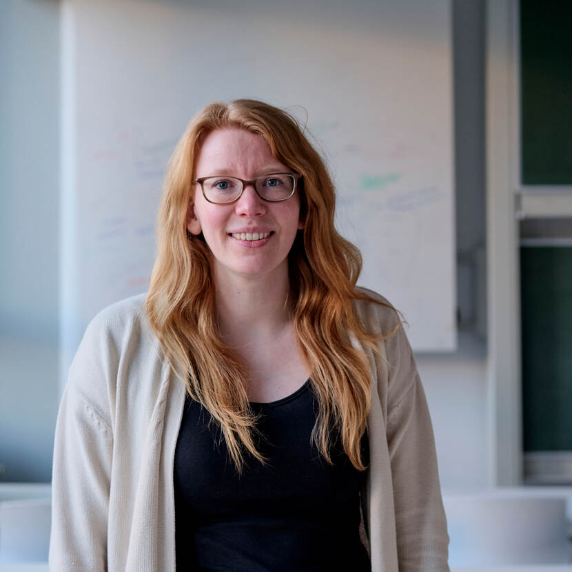 Banner Mirte Kuipers, blond haar en bril,  staand voor een whiteboard